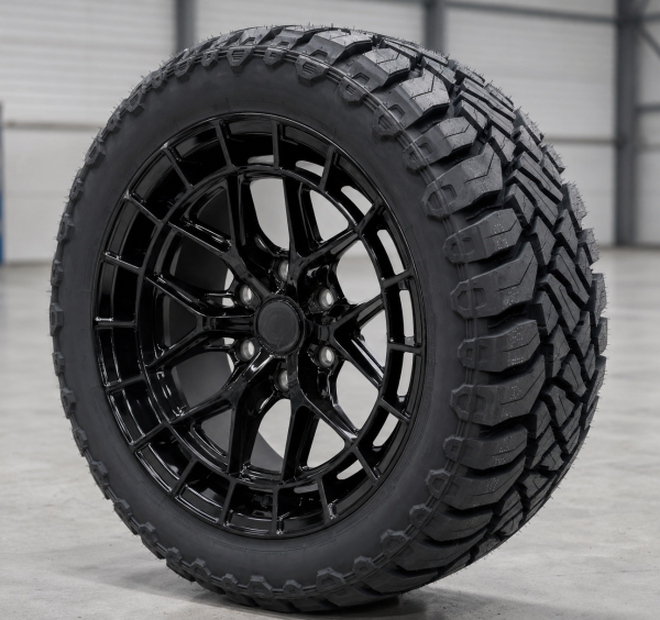 20-inch gloss black multi-spoke bakkie wheel fitted with rugged terrain tyre in a grey warehouse setting.