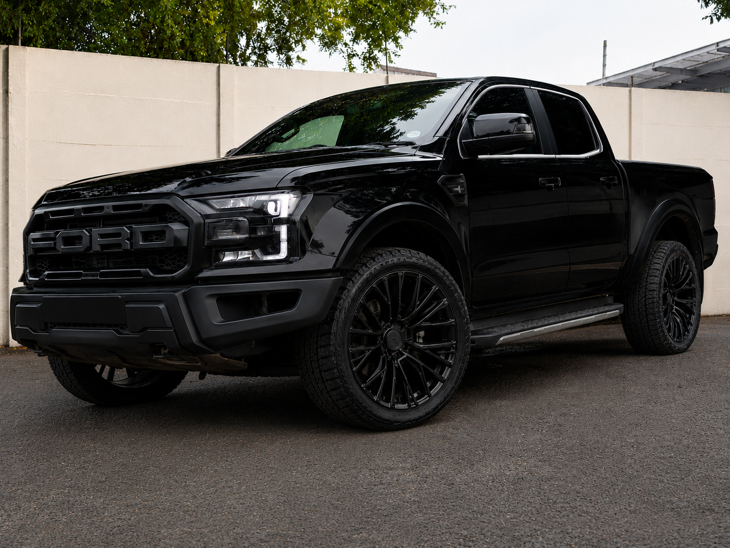 Black Ford Ranger Raptor fitted with 17 inch black multi-spoke alloy wheels and new tyres in a modern outdoor setting