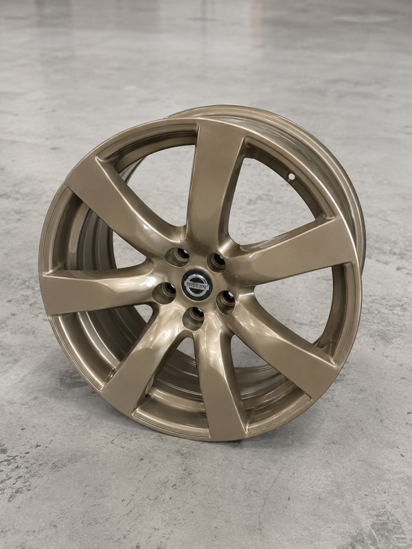 20 inch genuine Nissan Skyline GT-R OEM alloy wheel refinished in a custom bronze metallic finish displayed in a warehouse setting