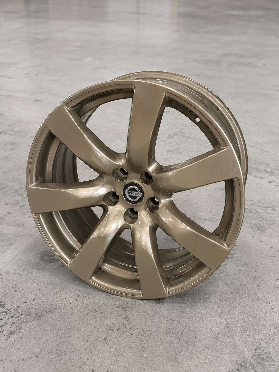 20 inch genuine Nissan Skyline GT-R OEM alloy wheel refinished in a custom bronze metallic finish displayed in a warehouse setting